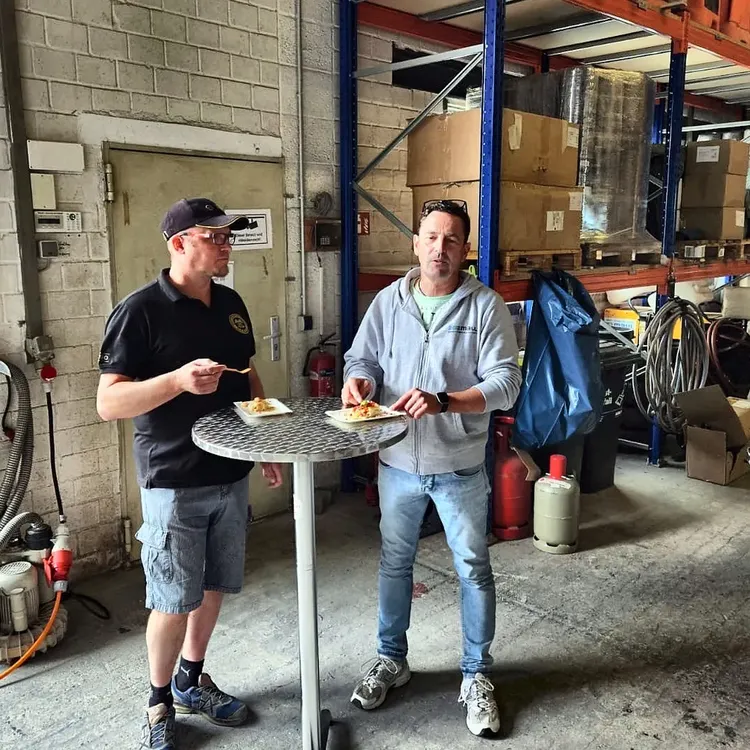 Zwei Mitarbeiter essen Crêpes an einem Stehtisch im Hallentor.