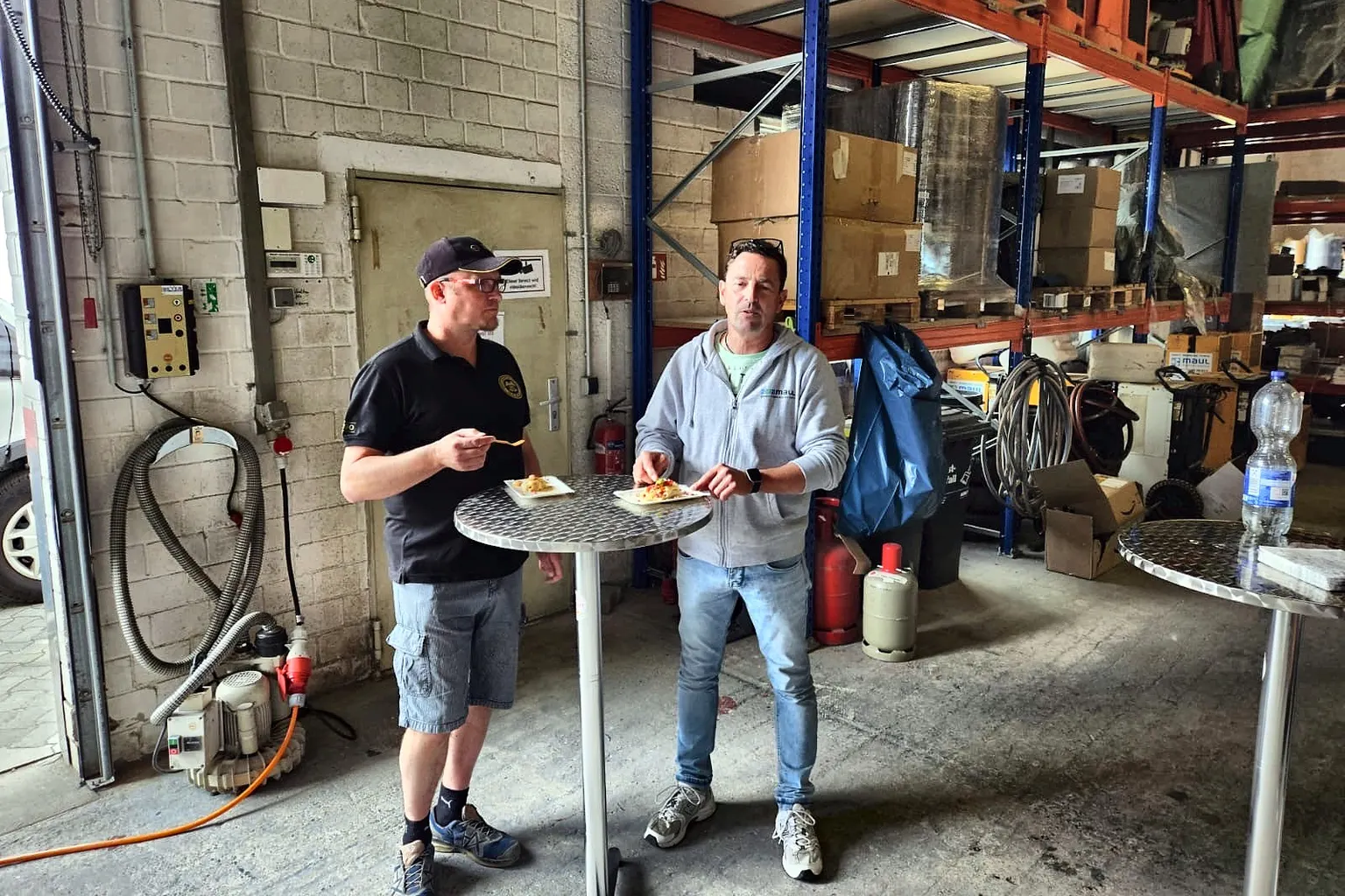 Zwei Mitarbeiter essen Crêpes an einem Stehtisch im Hallentor.