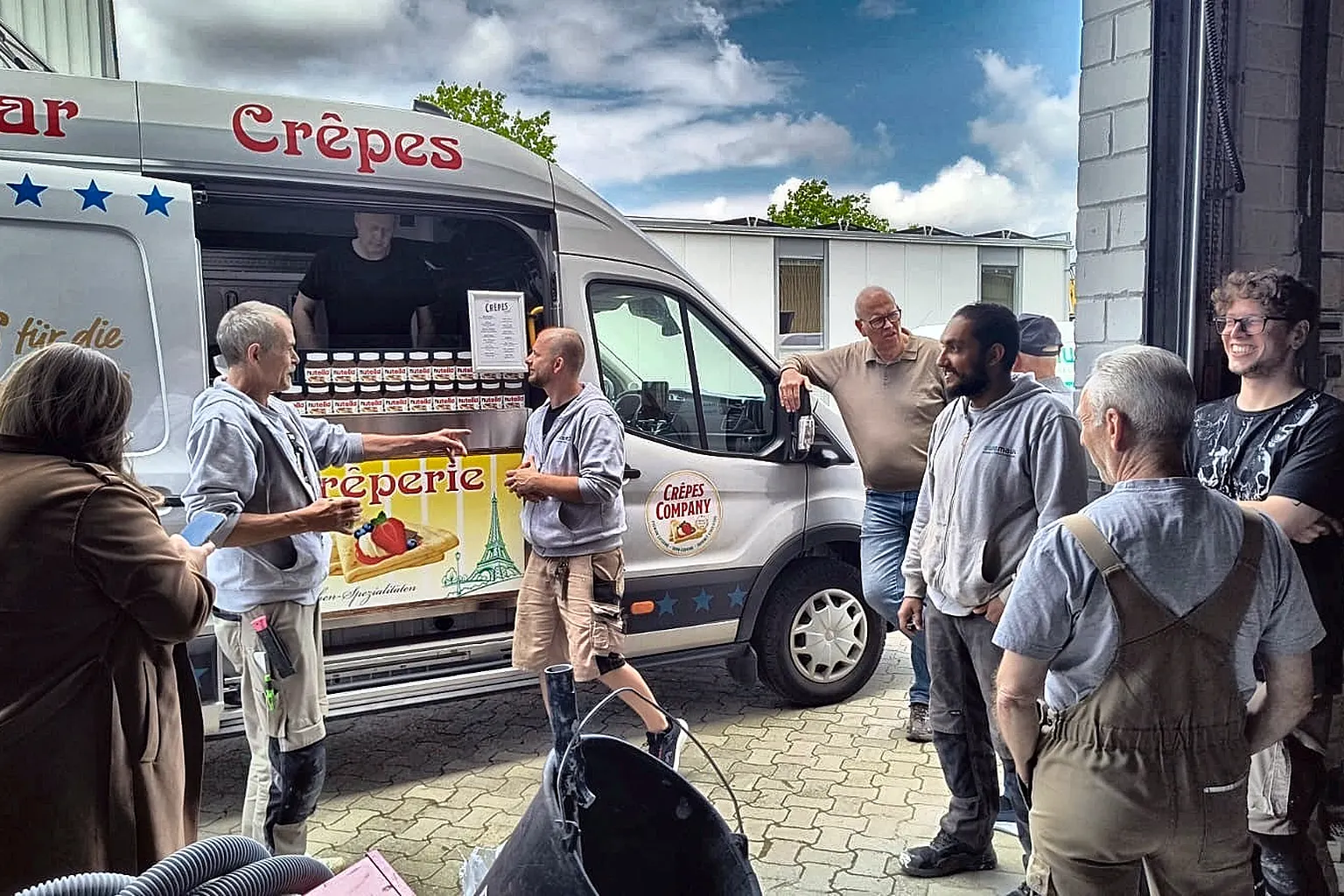 Gruppe von Mitarbeitenden im Gespräch in der Lagerhalle.